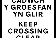 Cars parked near a school in Cardiff, Wales, with a no-idling sign in the background