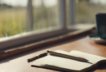 AI-generated image: A wooden table with a notebook and a pen are in the foreground.
