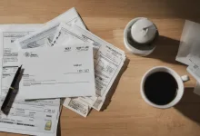 AI-generated image: A top-down shot of a wooden table with a pile of documents, a cup of coffee, and a pen.