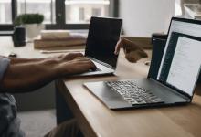 AI-generated image: Two laptops are placed side-by-side on a light-colored wooden table.
