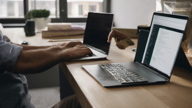 AI-generated image: Two laptops are placed side-by-side on a light-colored wooden table.