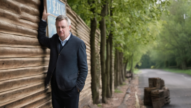 AI-generated image: A middle-aged man is leaning against a wooden fence.