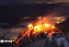Orange flames light up an old building in the alps