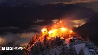 Orange flames light up an old building in the alps