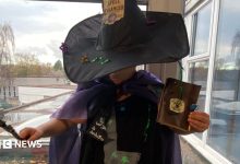 Child dressed as a witch in a homemade Halloween costume featuring a black hat, purple cape, wand and handmade accessories.