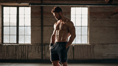 AI-generated image: A muscular man is standing in a dark room with large windows.