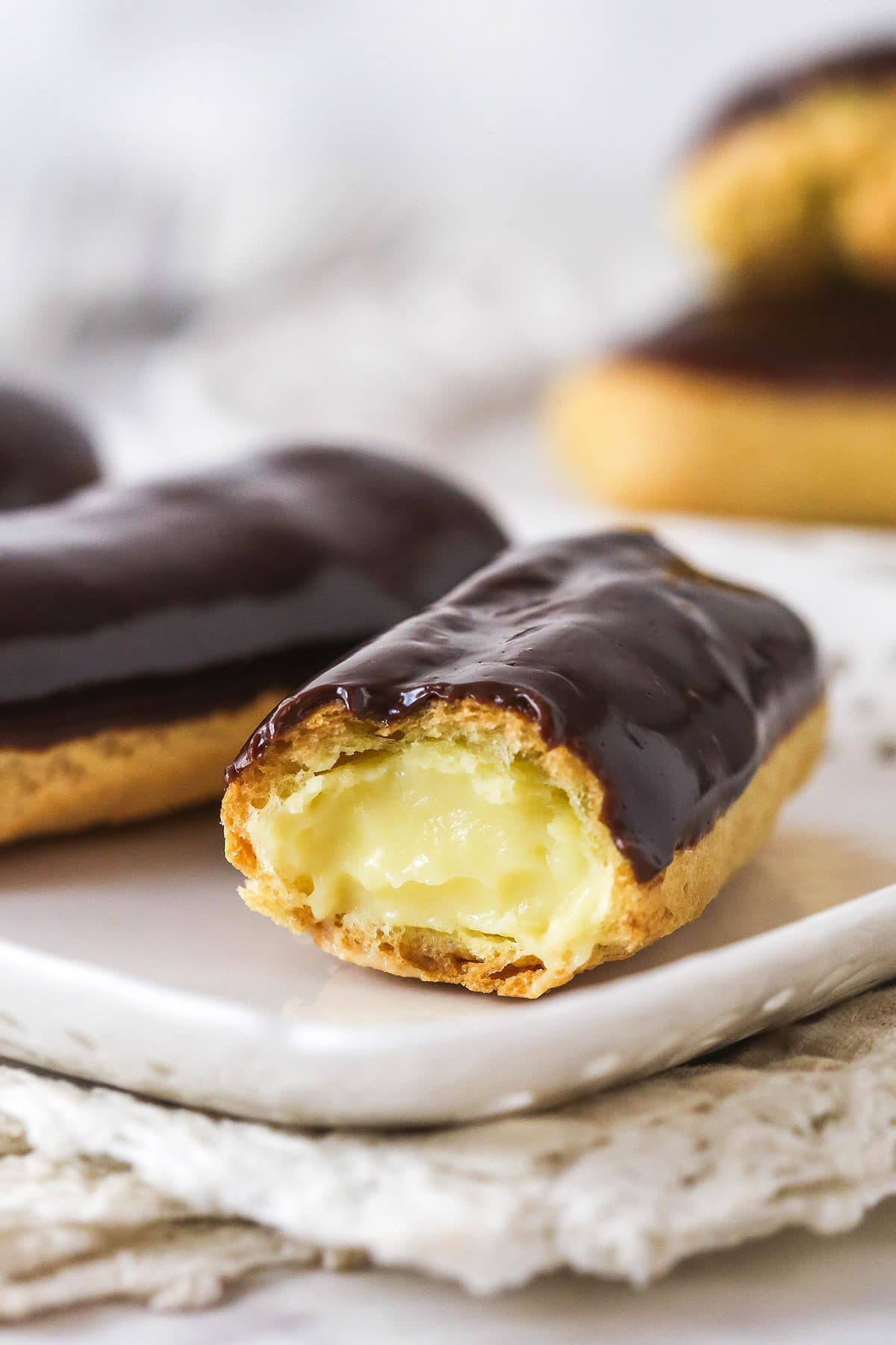 Homemade eclairs on a plate, one missing a bit to show the inside
