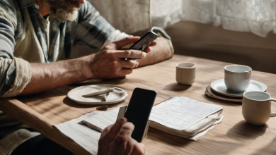 AI-generated image: A man with a beard and gray hair is sitting at a wooden table.