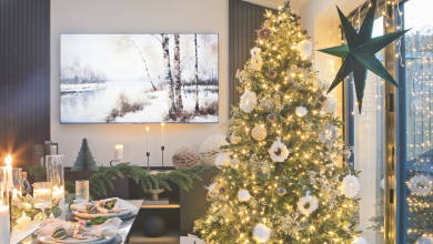 Christmas tree decorating with white ornaments and warm gold lighting next to a festive tablescape.