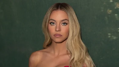 Sydney Sweeney in a red off-shoulder dress against a green backdrop.