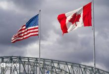 The US and Canada flags flutter next to the Blue Water Bridge border crossing in Point Edward, Ontario, on 24 October 2025.