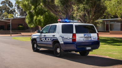 AI-generated image: A white police vehicle, with blue lights on the roof and a ‘POLICE’ sign on the side, is parked on an asphalt road.
